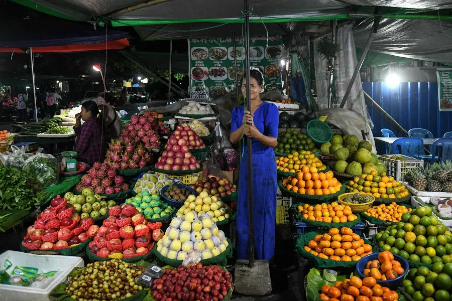 A fruit vendor waits for customers at a night market in Mandalay, Myanmar, on 23 October 2024. (AFP)