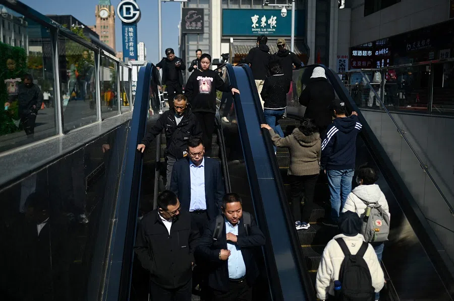People ride an escalator at the entrance of a subway station in Beijing on 23 October 2024. (Wang Zhao/AFP)