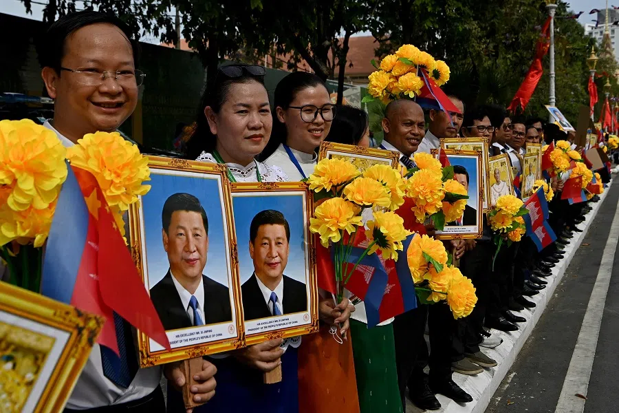 Cambodians hold portraits of China’s President Xi Jinping and Cambodia’s King Norodom Sihamoni during a welcome ceremony in front of the Royal Palace in Phnom Penh, 17 April 2025.