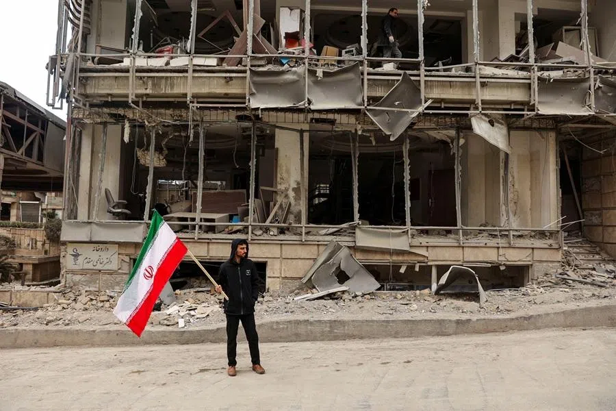 A man holds an Iranian flag following an Israeli and the US strike on Gandhi Hotel Hospital, amid the US-Israel conflict with Iran, in Tehran, on 2 March 2026.