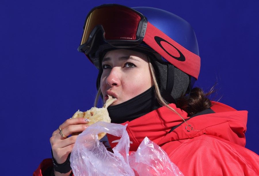 Eileen Gu munches on jiucai hezi after her run in the freestyle skiing competition at the 2022 Beijing Olympics, Genting Snow Park, Zhangjiakou, China, 14 February 2022. (Mike Blake/Reuters)