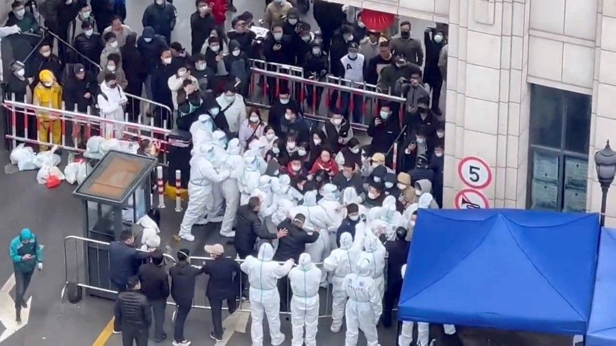 Residents confront workers in protective suits who are blocking the entrance of a residential compound, amid the Covid-19 outbreak in Shanghai, China, in this still image obtained from a social media video released 30 November 2022. (Reuters)