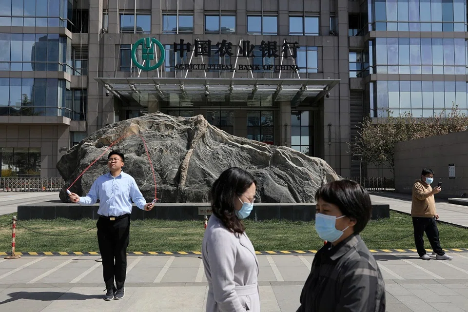 People are seen in front of an office building of Agricultural Bank of China, in Beijing, China on 29 March 2021. (Tingshu Wang/Reuters)