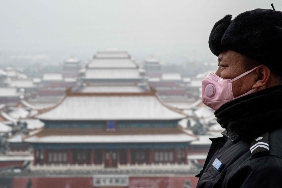 A security guard in a mask looks out from the Jingshan park overlooking the Forbidden city (center) after a snowfall in Beijing, February 2020. (Nicolas Asfouri/AFP)