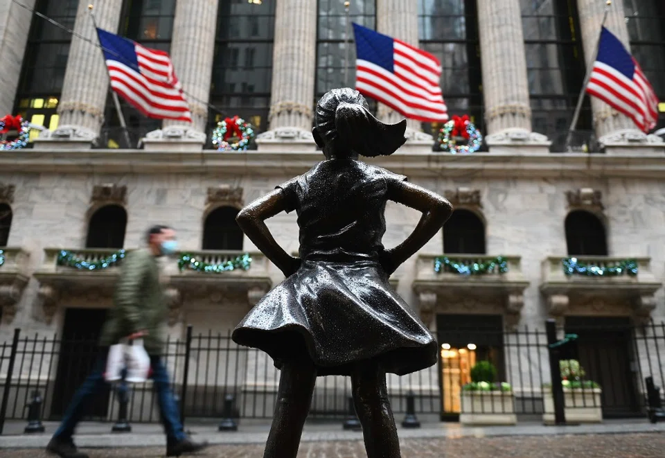 People walk past the New York Stock exchange (NYSE) and the 'Fearless Girl' statue at Wall Street after heavy rainfall on 30 November 2020 in New York City, US. (Angela Weiss/AFP)