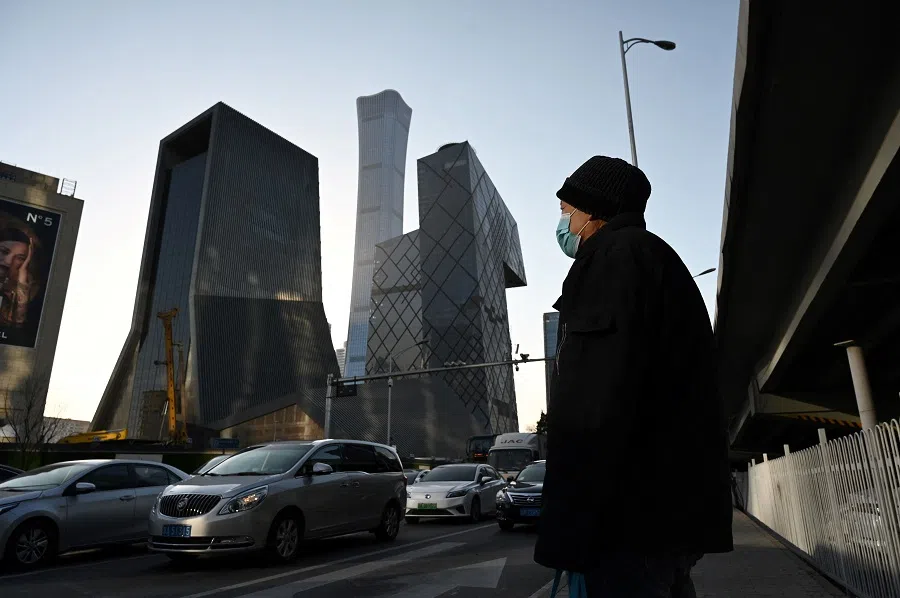 This file photo taken on 16 December 2021 shows a man waiting to cross a road in the central business district in Beijing, China. (Greg Baker/AFP)