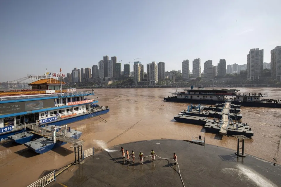 Workers use a fire hose to wash away mud left by receded floodwaters off the Chaotianmen docks in Chongqing, 28 July 2020. (Qilai Shen/Bloomberg)