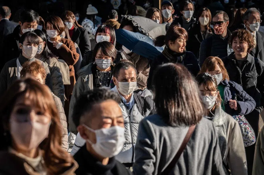 People cross a street in Ginza district of Tokyo on 20 December 2022. (Yuichi Yamazaki/AFP)