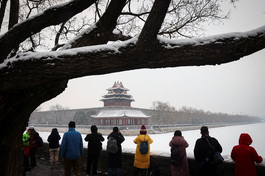 People take pictures of the Forbidden City after an overnight snowfall in Beijing, China, 22 January 2022. (Thomas Peter/Reuters)