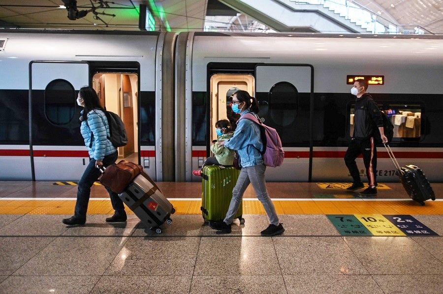 People wearing face masks as a preventive measure against the Covid-19 coronavirus arrive to board a train heading to Shanghai at Wuhan Railway Station in Wuhan, China, on 21 April 2020. (Hector Retamal/AFP)
