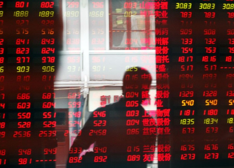 A man is reflected in an electronic stock board showing stock information at a securities exchange house in Shanghai. (Qilai Shen/Bloomberg)