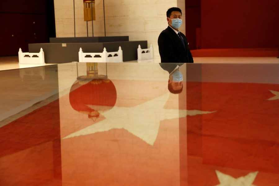 A security guard wearing a face mask stands near an exhibit of a flag of China, which has been raised at the founding ceremony of People's Republic of China in 1949, at the National Museum in Beijing, 16 May 2020. (Tingshu Wang/REUTERS)