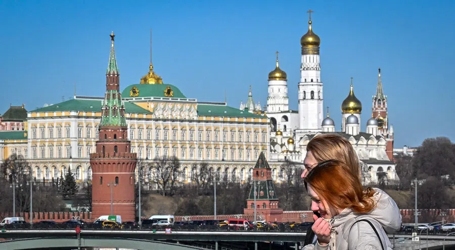 People walk on a bridge near the Kremlin in central Moscow, Russia, on 18 March 2022. (AFP)