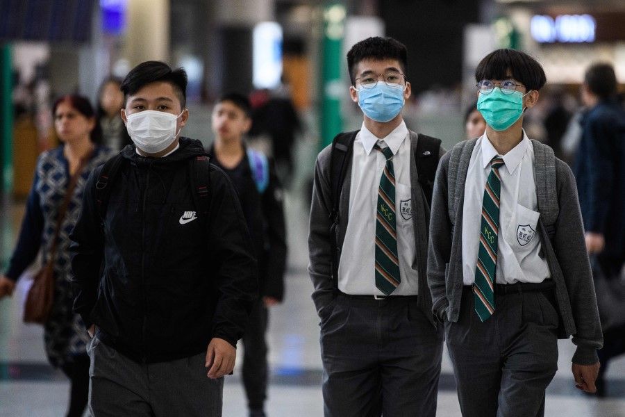 Students at Hong Kong's international airport. Hong Kong's schools will remain closed until 20 April. (Anthony Wallace/AFP)