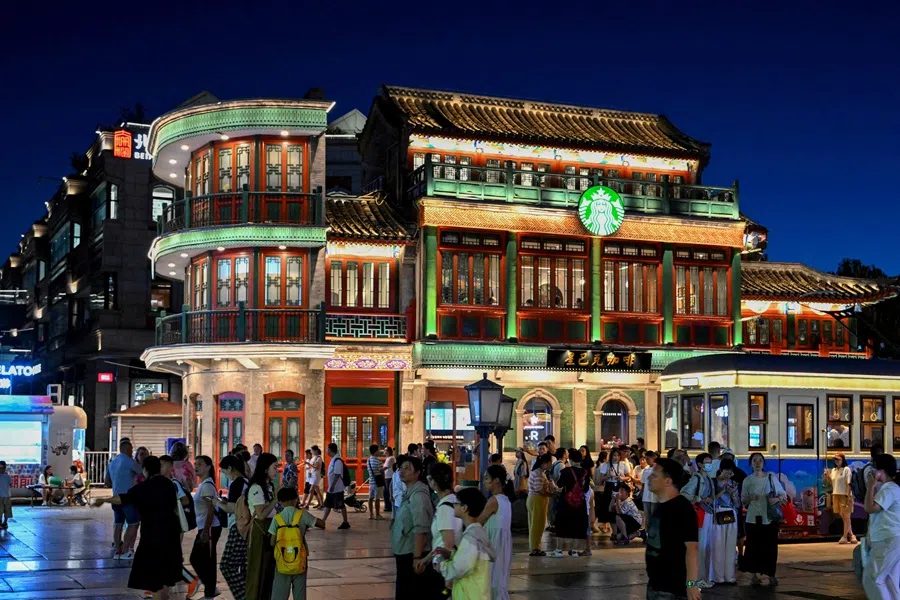 People walk along Qianmen promenade in Beijing on 5 July 2025. (Adek Berry/AFP)