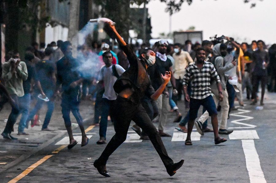 A demonstrator throws back a tear gas canister fired by police to disperse students taking part in an anti-government protest demanding the resignation of Sri Lanka's President Gotabaya Rajapaksa over the country's crippling economic crisis, in Colombo, Sri Lanka, on 29 May 2022. (Ishara S. Kodikara/AFP)