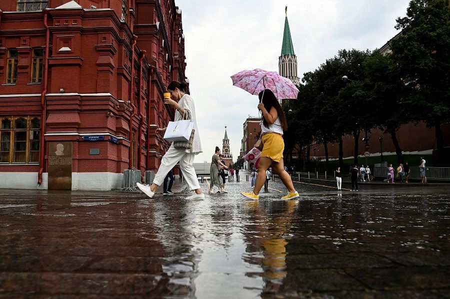 People walk through a puddle after the rain in downtown Moscow, Russia on 10 August 2021. (Kirill Kudryavtsev/AFP)