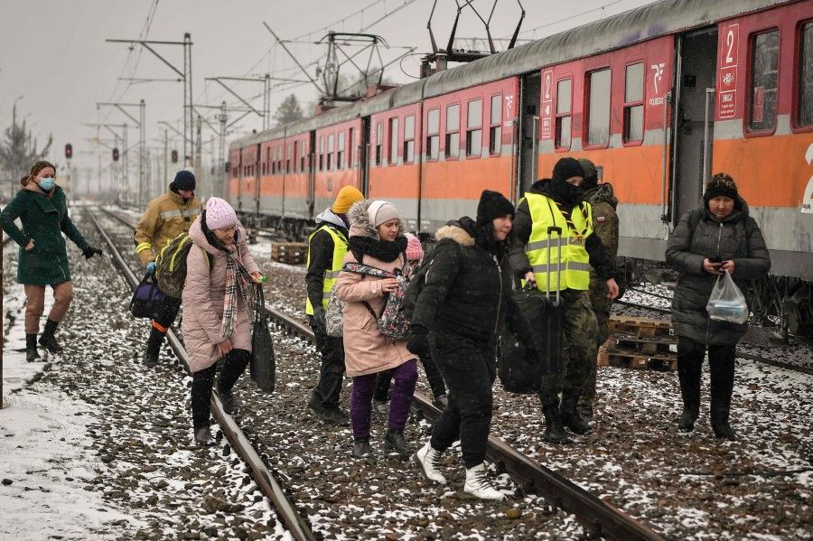 Newly arrived refugees are assisted by volunteers to board a train bound for Krakow just after crossing the border into Poland from Ukraine at the border crossing in Medyka, eastern Poland, on 9 March 2022. (Louisa Gouliamaki/AFP)