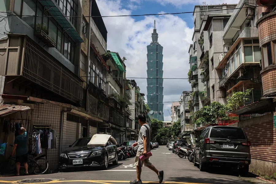 A pedestrian crosses a street as the Taipei 101 skyscraper is seen in the background in Taipei on 9 September 2026.