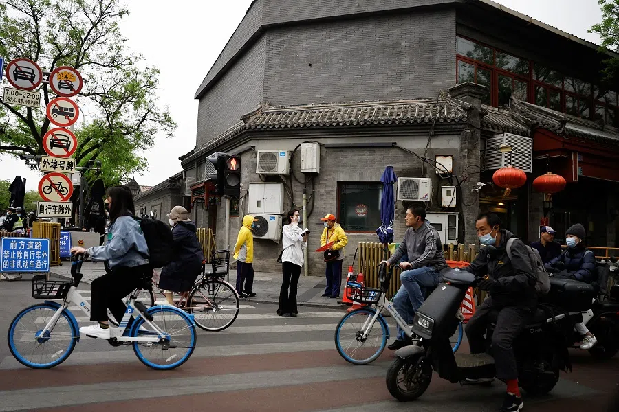 People ride bicycles and scooters on a street during morning rush hour, in Beijing, China, 20 April 2023. (Tingshu Wang/Reuters)