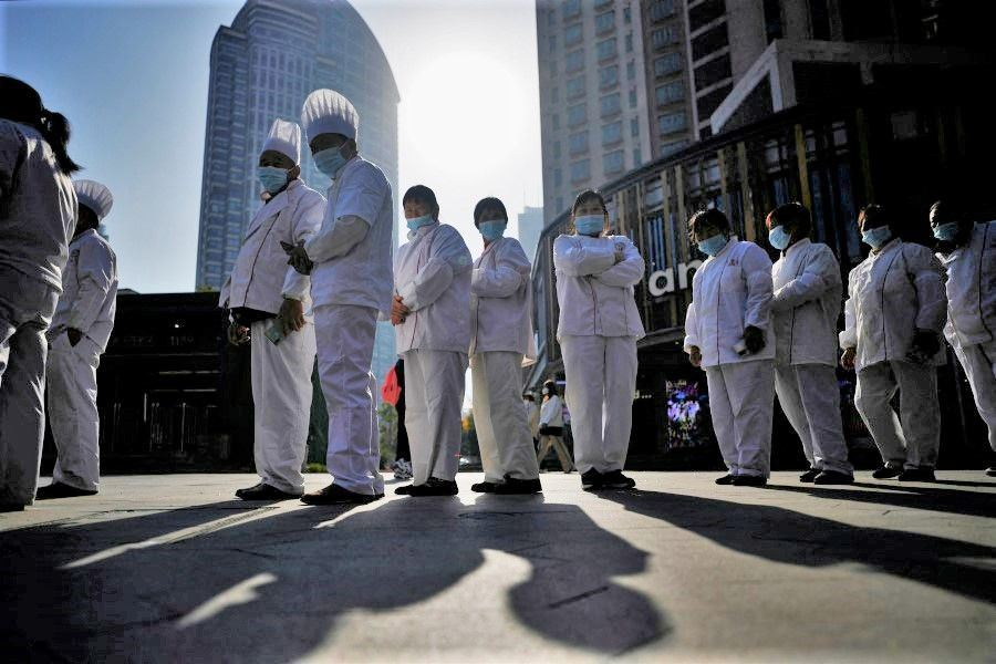 Restaurant workers wearing face masks line up to get tested for Covid-19 at a nucleic acid testing site, as Covid-19 outbreaks continue in Shanghai, China, 13 December 2022. (Aly Song/Reuters)