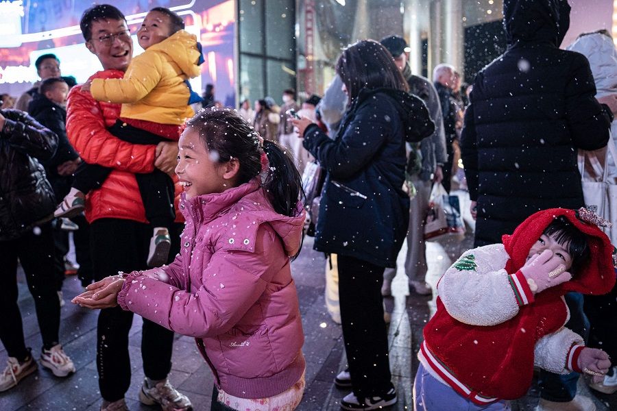 This photo taken on 24 December 2023 shows children playing with artificial snow in Guangzhou, in China's southern Guangdong province. (AFP)