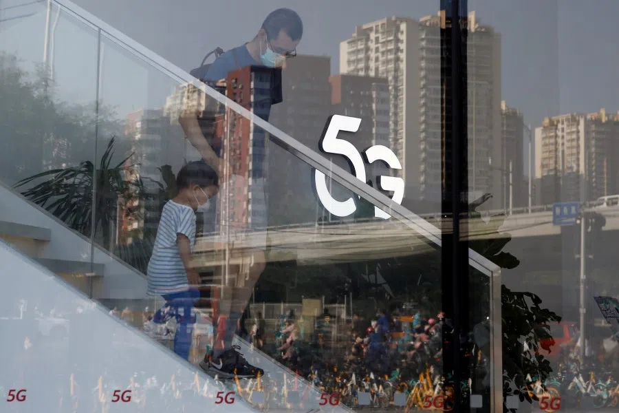 A man and a child wearing face masks following the coronavirus disease (COVID-19) outbreak walk past a 5G sign inside a Huawei store at a shopping mall in Beijing, 14 July 2020. (Tingshu Wang/REUTERS)