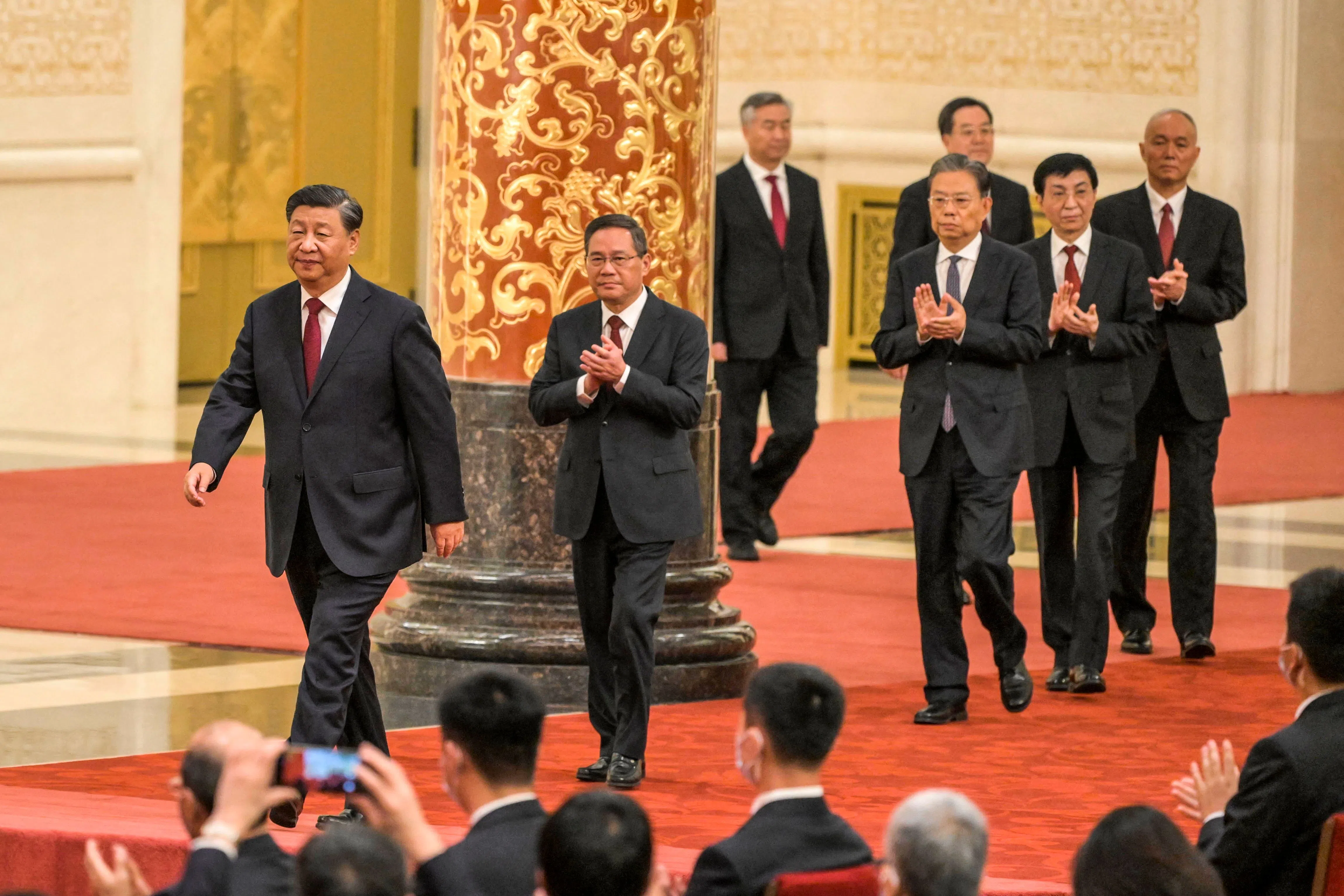 China's President Xi Jinping (left) walks with (second from left to right) Li Qiang, Li Xi, Zhao Leji, Ding Xuexiang, Wang Huning and Cai Qi, members of the Chinese Communist Party's new Politburo Standing Committee, the nation's top decision-making body, as they meet the media in the Great Hall of the People in Beijing on 23 October 2022.