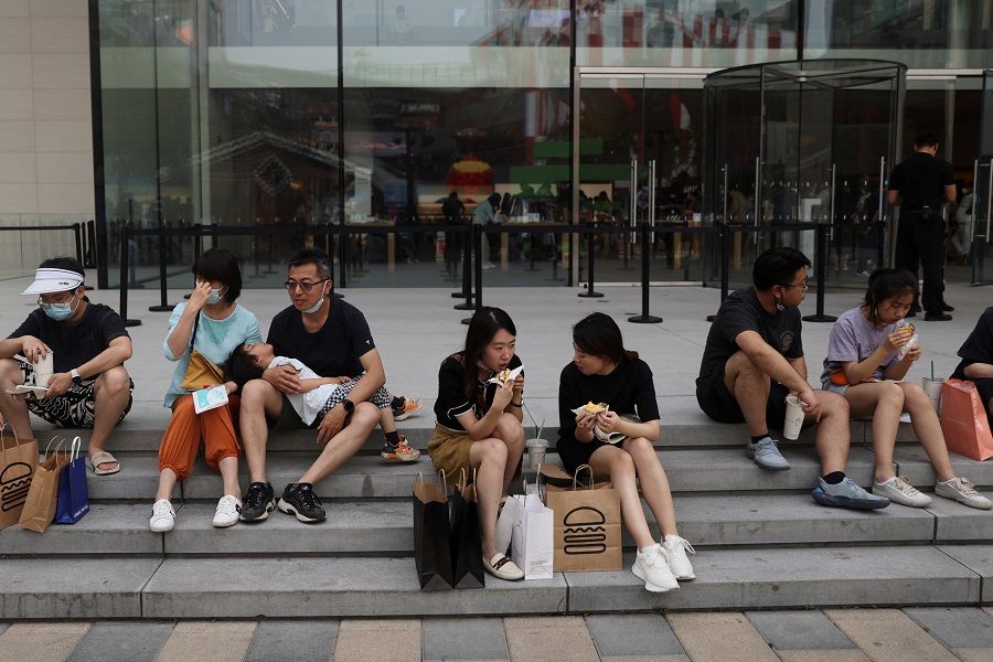 People rest and eat food on the stairs at a shopping area in Beijing, China, 3 June 2022. (Tingshu Wang/Reuters)