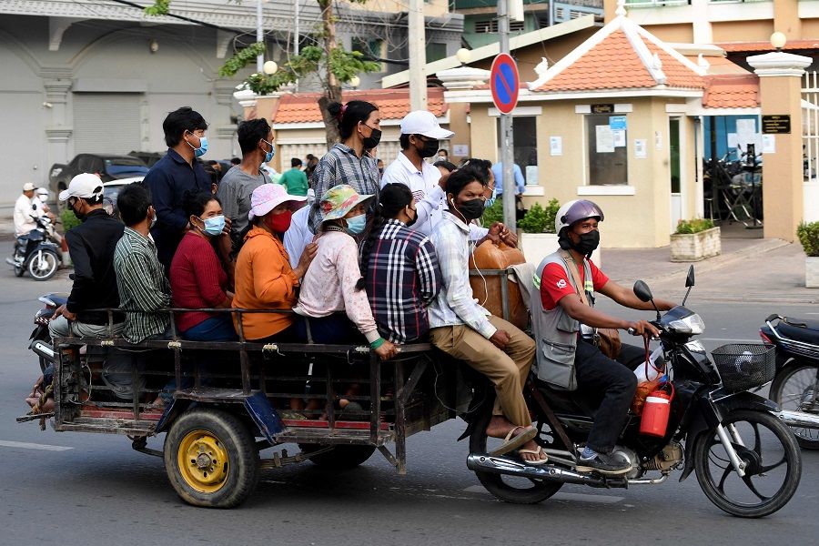 People sit on a cart pulled by a motorbike travelling along a street in Phnom Penh, Cambodia, on 18 August 2021. (Tang Chhin Sothy/AFP)