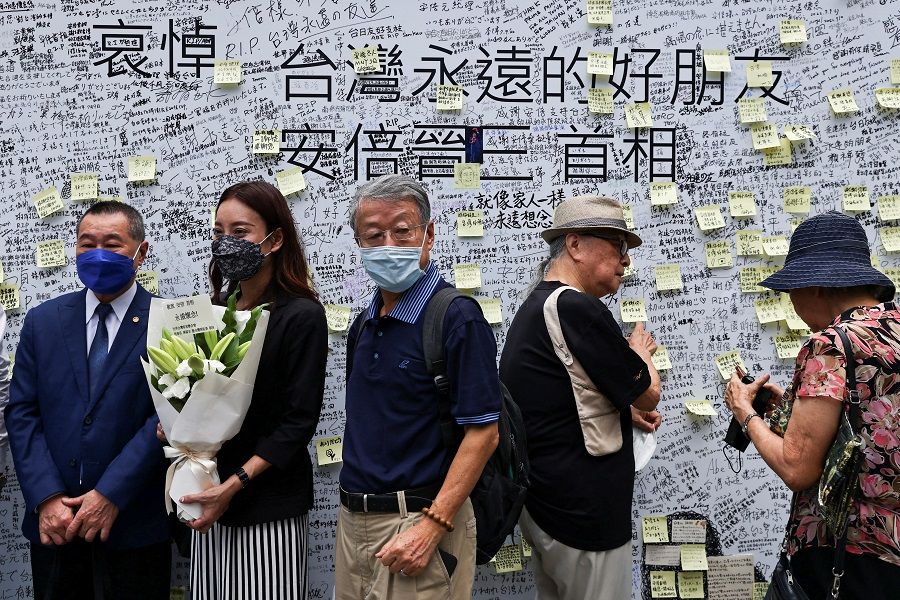 People stand in front of a memorial wall for late former Japanese Prime Minister Shinzo Abe, who was shot while campaigning for a parliamentary election, in Taipei, Taiwan, 11 July 2022. (Ann Wang/Reuters)