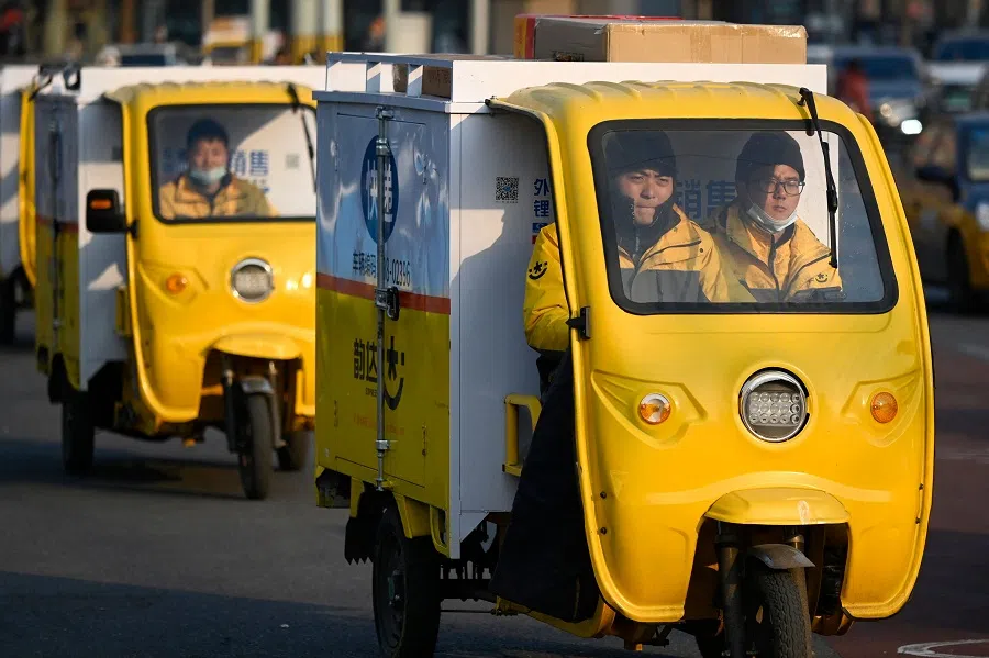 Delivery workers drive their tricycles along a street in Beijing, China, on 5 January 2022. (Wang Zhao/AFP)
