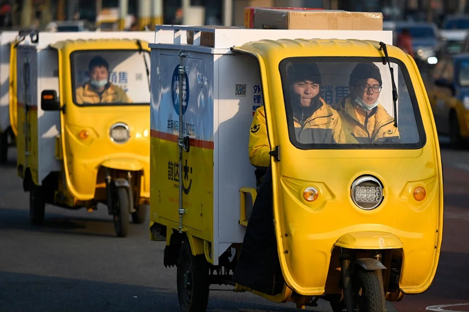 Delivery workers drive their tricycles along a street in Beijing, China, on 5 January 2022. (Wang Zhao/AFP)