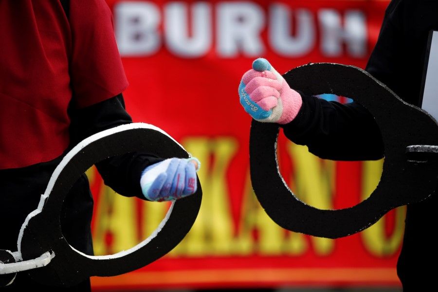 Members of Indonesian Trade Unions carry giant handcuffs during a protest against the government's labor reforms in a "job creation" bill in Jakarta, Indonesia, 10 November 2020. (Willy Kurniawan/REUTERS)