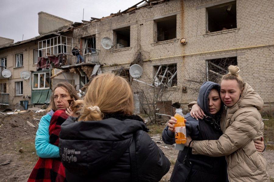 Locals react as they stand at the impact crater of a Russian S-300 missile that hit next to an apartment building in Peresichne near Kharkiv, amid Russia's ongoing attack on Ukraine, on 7 October 2023. (Thomas Peter/Reuters)