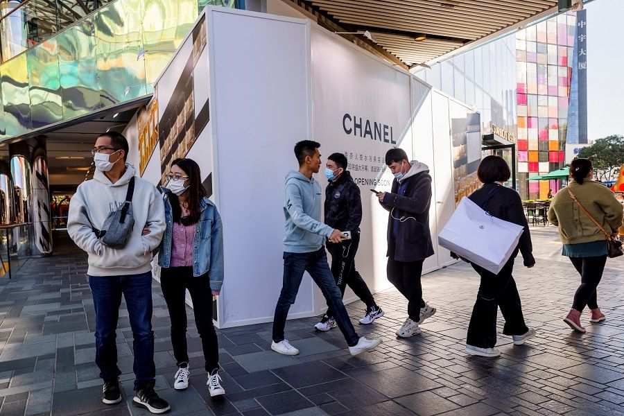 People walk in an upscale shopping district in the Sanlitun area in Beijing, China, 19 October 2021. (Thomas Peter/Reuters)