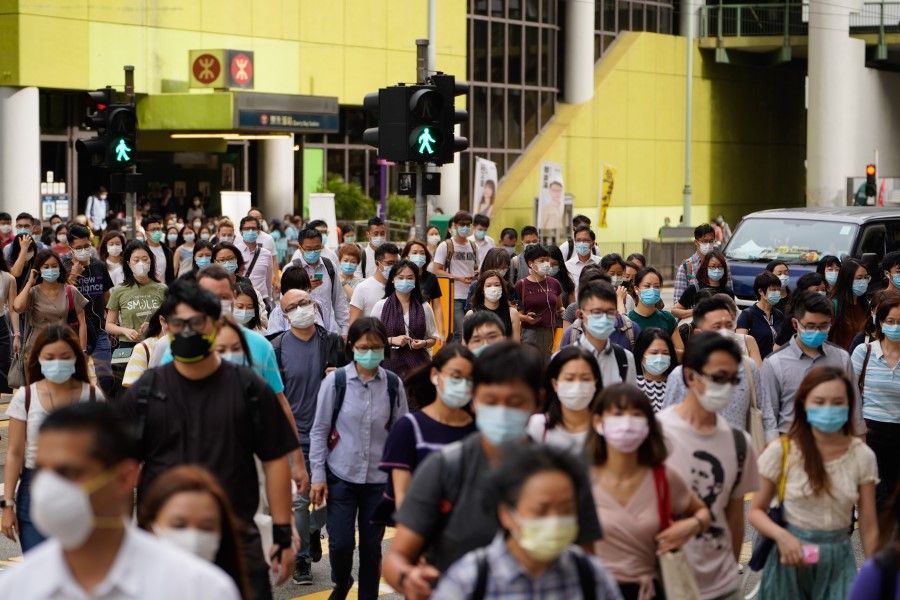 Pedestrians wearing protective masks walk across a road in Hong Kong, China, on 10 July 2020. (Roy Liu/Bloomberg)
