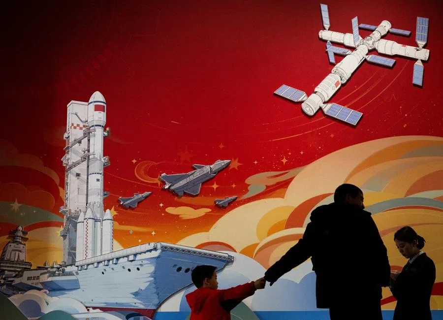 Visitors stand in front of a mural depicting aircraft carrier, fighter jets and spacecraft at an exhibition on China’s manufacturing achievements at the National Museum in Beijing, China, on 24 March 2026. (Maxim Shemetov/Reuters)