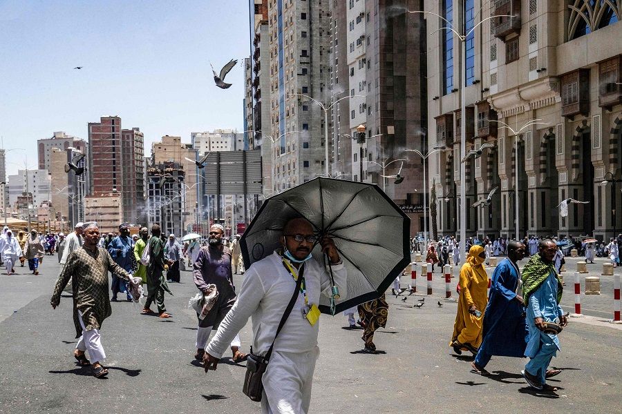 People walk along a street equipped with mist sprayers as they face the very hot desert weather, during the Hajj in Saudi Arabia's holy city of Mecca, on 7 July 2022. (Delil Souleiman/AFP)