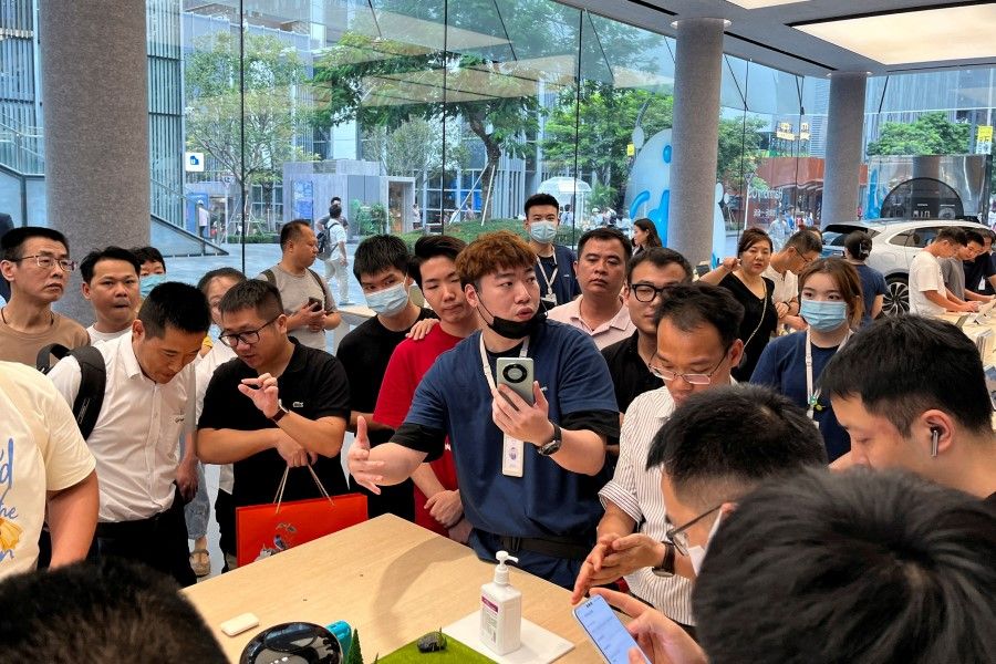 A staff member introduces the new Huawei Mate 60 smartphone to customers at the Huawei flagship store in Shenzhen, Guangdong province, China, on 30 August 2023. (David Kirton/Reuters)