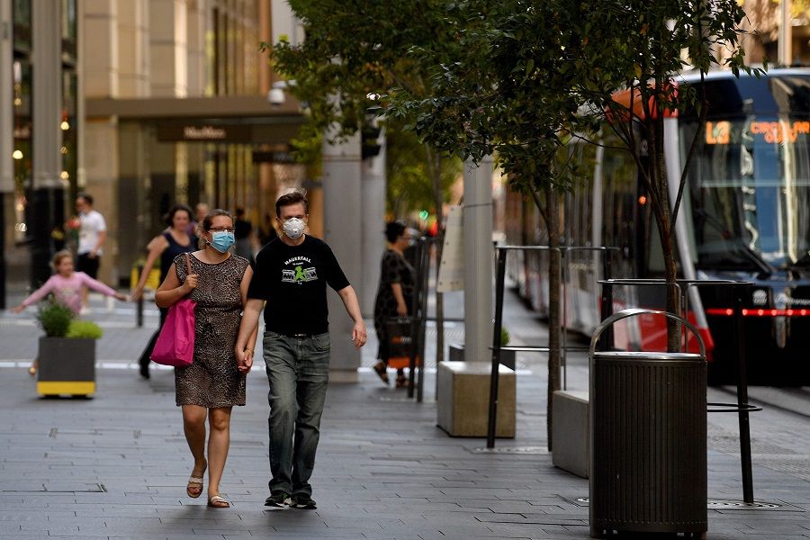 People wearing face masks walk in the empty streets of Sydney's central business district on 11 April 2020. (Saeed Khan/AFP)