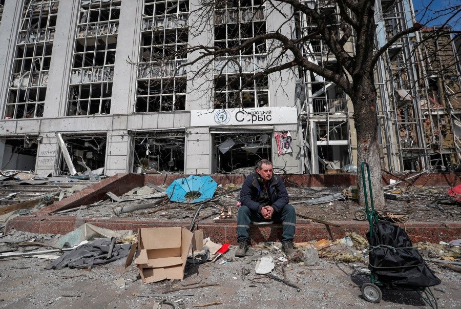 A resident looks on near a building destroyed in the course of the Ukraine-Russia conflict, in the southern port city of Mariupol, Ukraine, 10 April 2022. (Alexander Ermochenko/Reuters)