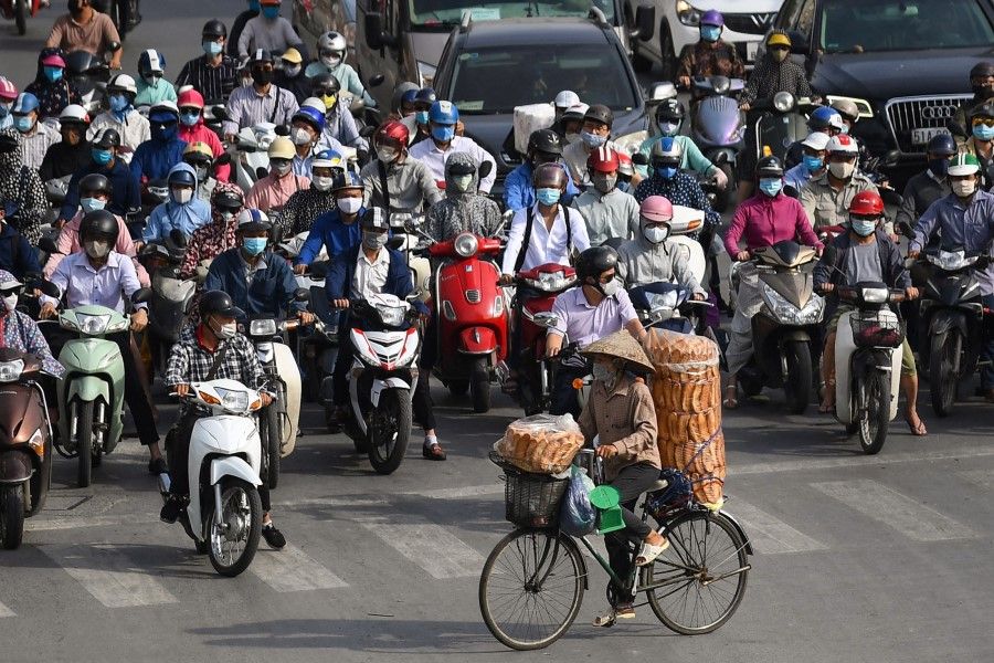 A bread vendor cycles past motorists waiting at a traffic light in Hanoi on 2 June 2021. (Nhac Nguyen/AFP)