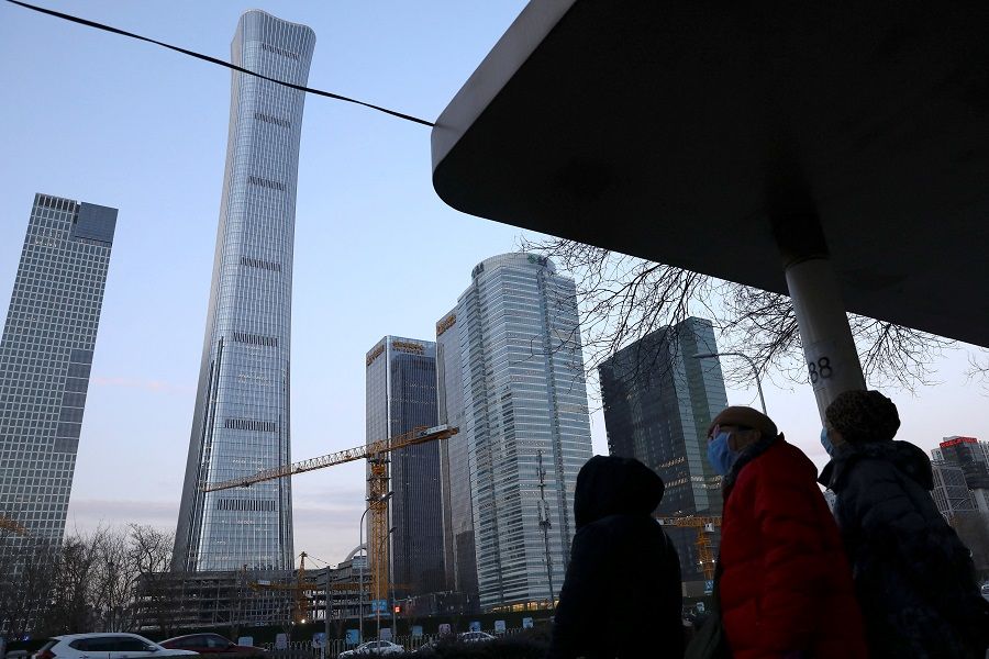 People wait at a bus stop in Beijing's Central Business District (CBD), China, 16 January 2022. (Tingshu Wang/Reuters)