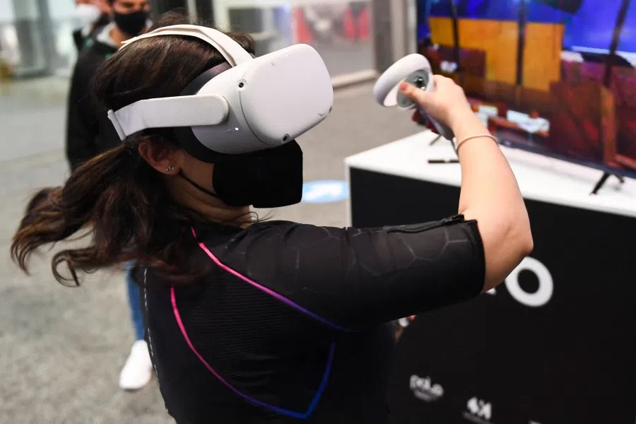An attendee demonstrates the Owo vest, which allows users to feel physical sensations during metaverse experiences such as virtual reality games, including wind, gunfire or punching, at the Consumer Electronics Show (CES) on 5 January 2022 in Las Vegas, Nevada. (Patrick T. Fallon/AFP)