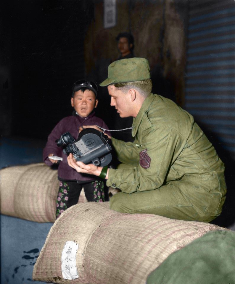 A US soldier captures on camera the moment Dachen residents arrive at Keelung, February 1955. The little boy in the photo is nervous about this strange new place, and the soldier consoles him.