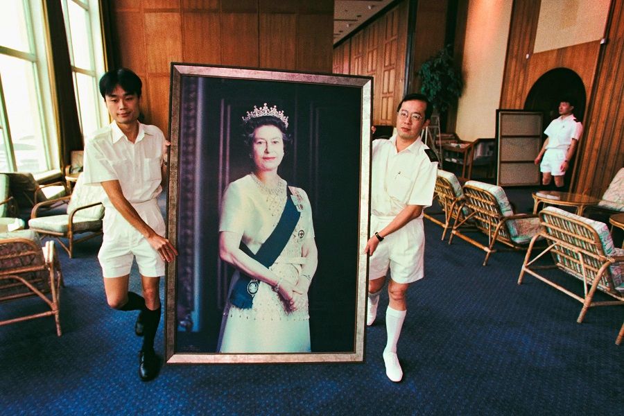This file photo taken on 16 June 1997 shows two Royal Navy sailors carrying a portrait of Britain's Queen Elizabeth II through HMS Tamar, the British Forces' Hong Kong headquarters, for the last time as her picture was taken down from the wall two weeks prior to the British territory's handover to Chinese rule on 1 July. (Stephen Shaver/AFP)