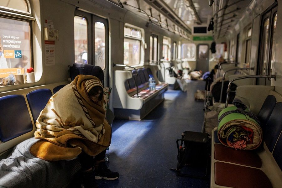 A woman is wrapped in a blanket in a subway train that is stationary in a metro station, which is being used as a bomb shelter, as Russia's attack on Ukraine continues, in Kyiv, Ukraine, 18 March 2022. (Thomas Peter/Reuters)