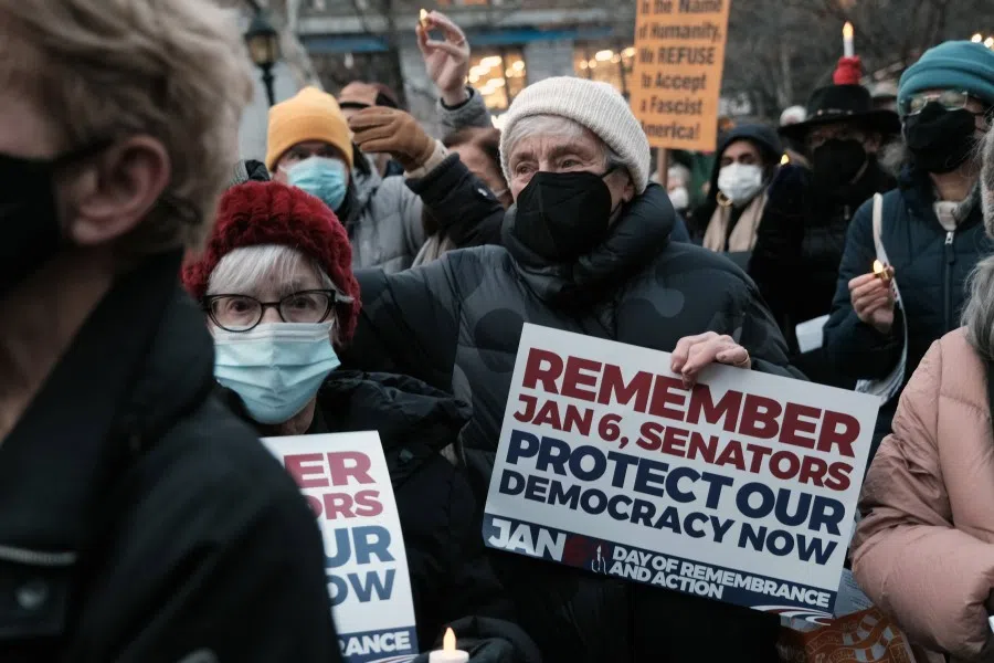 People hold signs and electric candles at a vigil to commemorate the first anniversary of the attack on the US Capitol by supporters of former President Donald Trump on 6 January 2022 in New York City. (Spencer Platt/AFP)