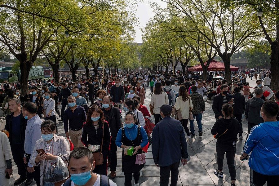 People wearing face masks as a preventive measure against the Covid-19 coronavirus walk outside the Forbidden City (not pictured) during the country's national "Golden Week" holiday in Beijing on 1 October 2020. (Nicolas Asfouri/AFP)